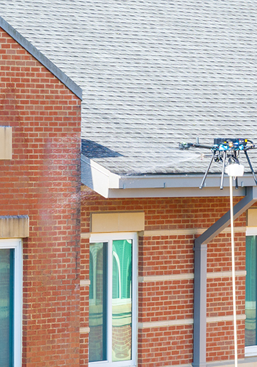 Drone cleaning removing stains from brick façade